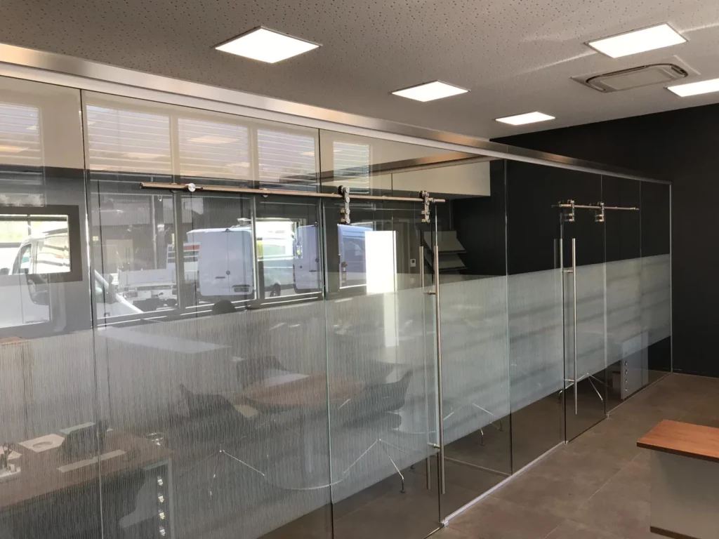 Film décoratif dépoli appliqué sur des cloisons vitrées de bureaux avec portes coulissantes en verre.