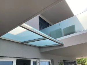 Marquise en verre opalin sur mesure avec structure métallique installée au-dessus d’une entrée d’habitation moderne.
